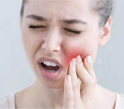 Woman holding her cheek in pain, indicating need for Emergency Dentist Paddington urgent dental care services