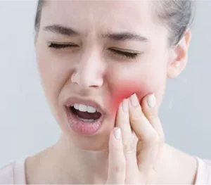 Woman holding her cheek in pain, seeking urgent relief from Emergency Dentist Marble Arch W2